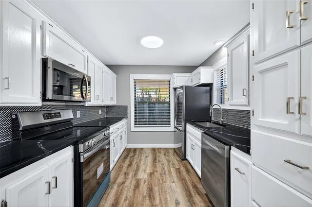 a kitchen with granite countertop a stove sink and microwave