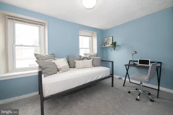 a bedroom with a bed a chair and next to a window