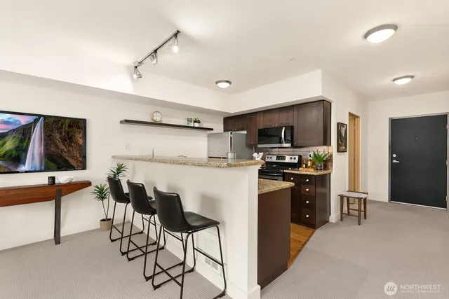 a kitchen with stainless steel appliances kitchen island granite countertop a refrigerator and a stove top oven