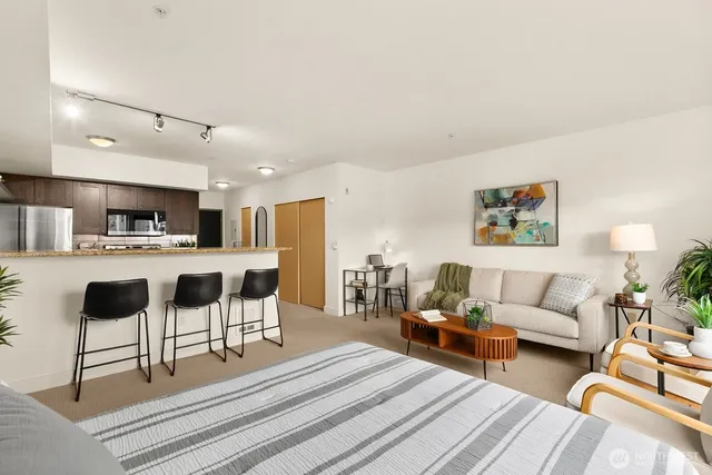 a living room with stainless steel appliances kitchen island granite countertop furniture and a couch