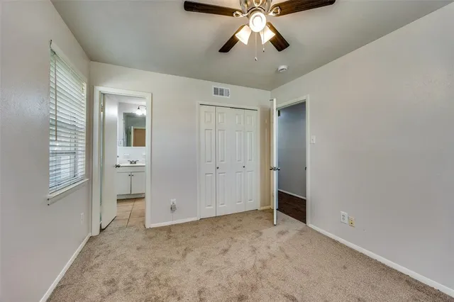 an empty room with chandelier fan and windows