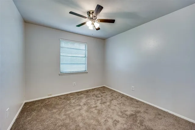 an empty room with chandelier fan and windows
