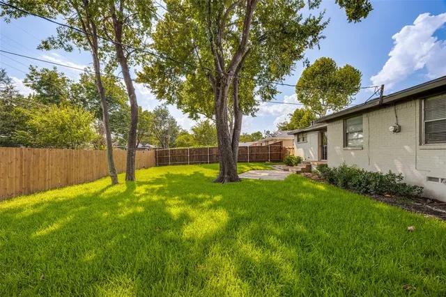 a view of backyard with large trees and flower plants