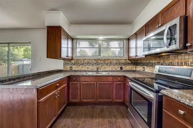 a kitchen with stainless steel appliances granite countertop wooden cabinets sink and stove top oven