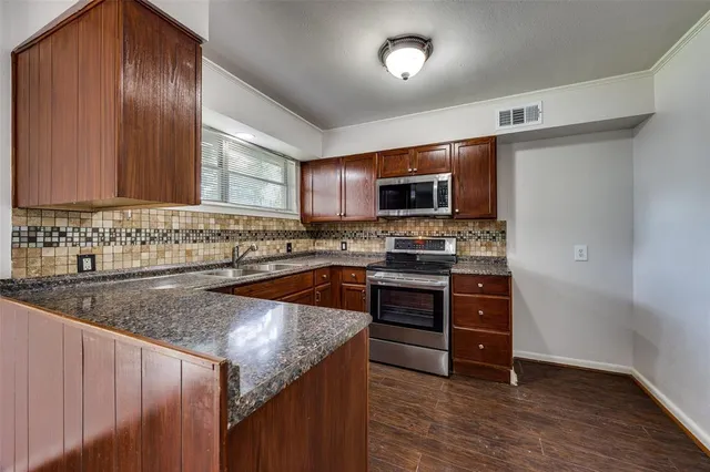 a kitchen with stainless steel appliances granite countertop a stove a sink and a microwave