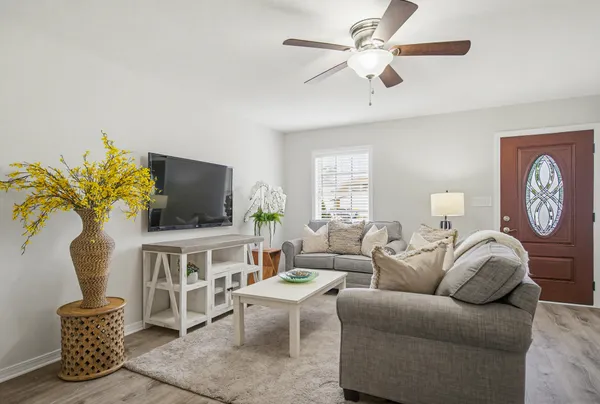 a living room with furniture a flat screen tv and a window