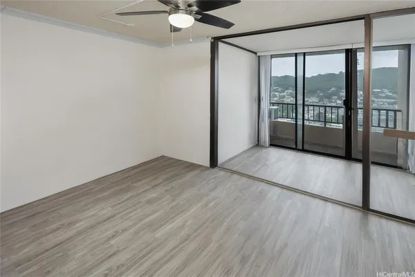 a view of an empty room with a window and wooden floor