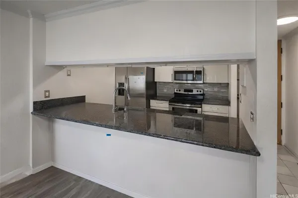a kitchen with granite countertop a refrigerator and a stove top oven