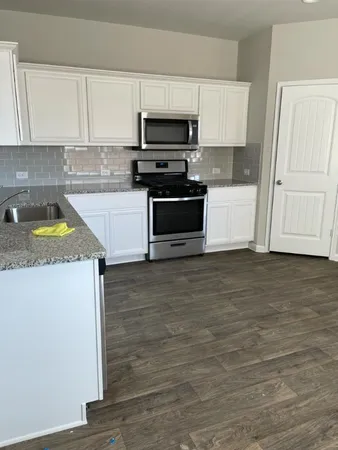 a kitchen with granite countertop a stove a microwave and a refrigerator