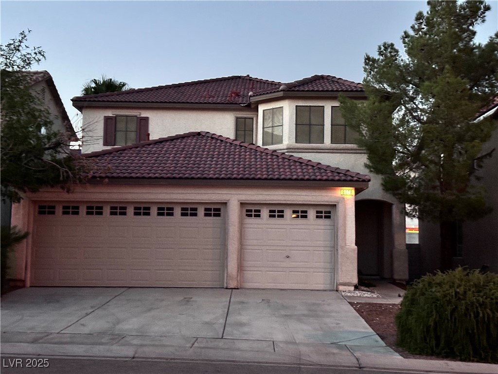 Mediterranean / spanish-style house with a tiled roof, concrete driveway, and stucco siding