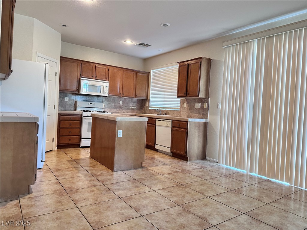 9676 Ridgebluff Avenue Las Vegas, NV 89148 - Photo 4 of 15 Kitchen with decorative backsplash, white appliances, tile counters, a kitchen island, and recessed lighting