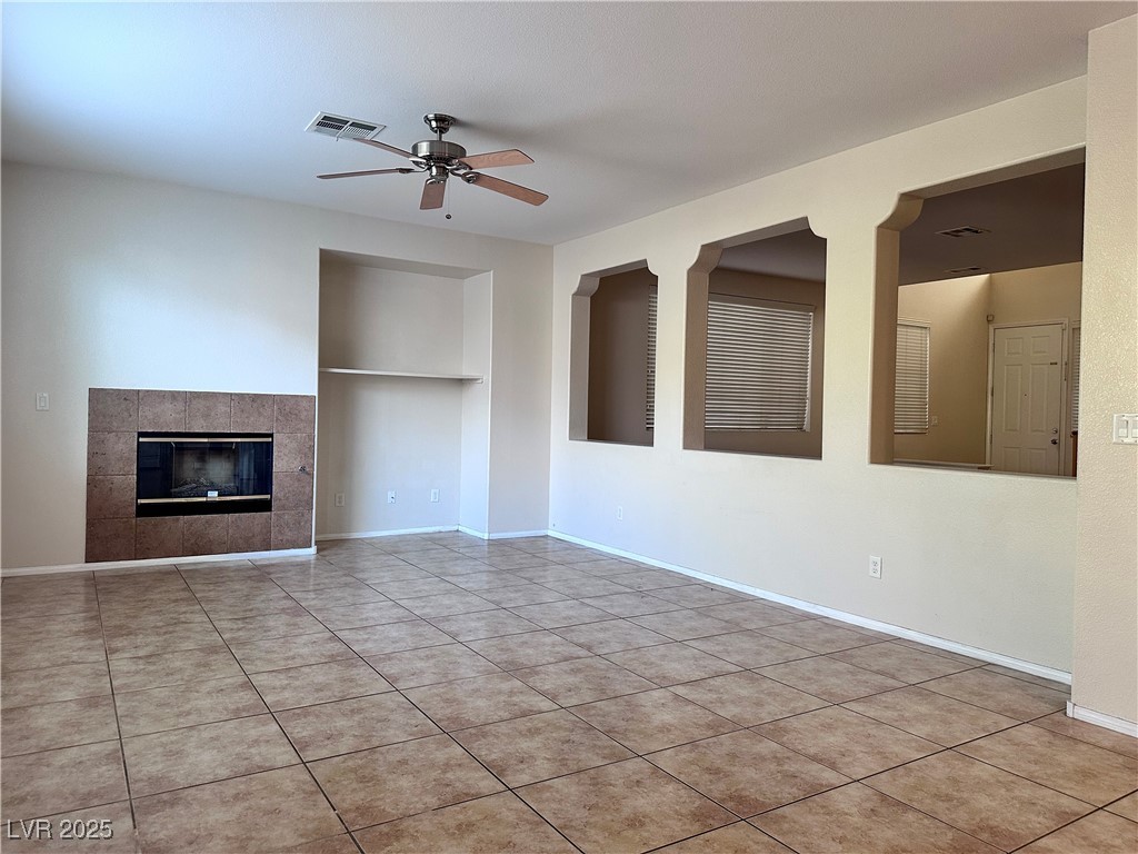 9676 Ridgebluff Avenue Las Vegas, NV 89148 - Photo 5 of 15 Unfurnished living room featuring a tile fireplace, light tile patterned flooring, and a ceiling fan