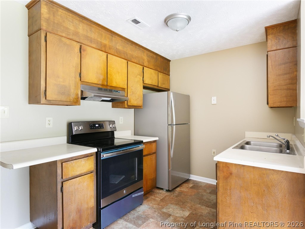 115 Eulon Loop, Unit A Raeford, NC 28376 - Photo 11 of 16 a kitchen with stainless steel appliances a stove a sink and a refrigerator