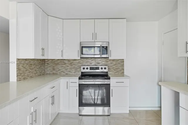 a kitchen with granite countertop white cabinets and stainless steel appliances