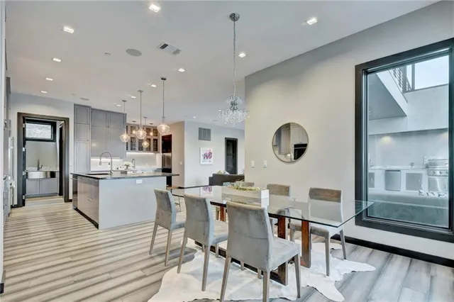 a kitchen with stainless steel appliances granite countertop a stove top oven a sink dishwasher a dining table and chairs with wooden floor