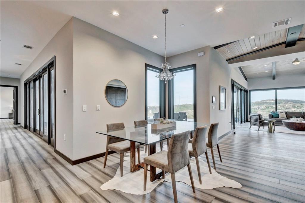 600 Barrett Lane Austin, TX 78733 - Photo 12 of 35 a dining room with wooden floor a glass table and chairs