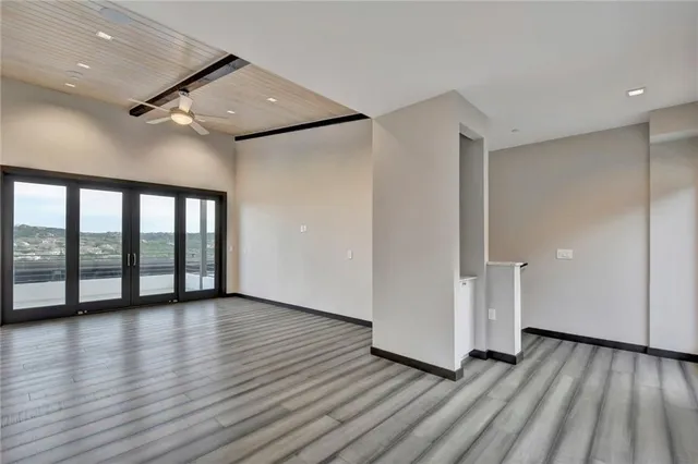 a view of an empty room with wooden floor and a window