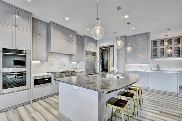a large kitchen with granite countertop lots of counter space white cabinets and stainless steel appliances