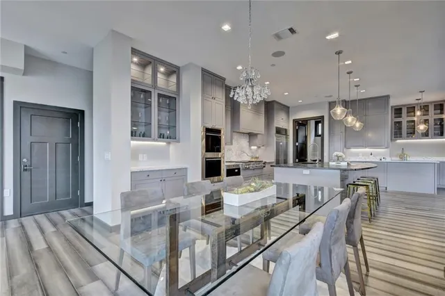 a large white kitchen with granite countertop a stove a sink a dining table and chairs