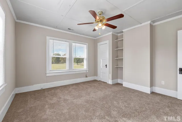 an empty room with windows and fan