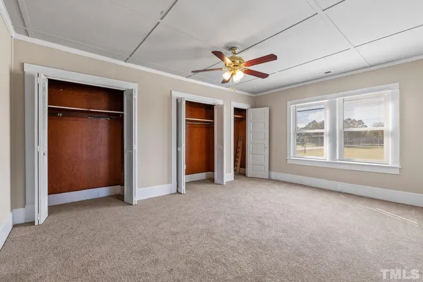 an empty room with windows and fan