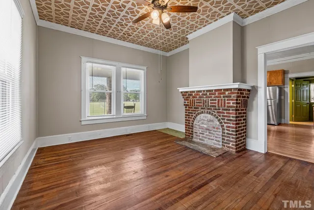 an empty room with wooden floor chandelier and windows