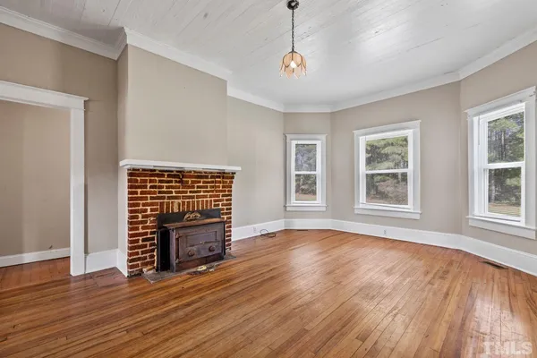 a view of an empty room with wooden floor fireplace and a window
