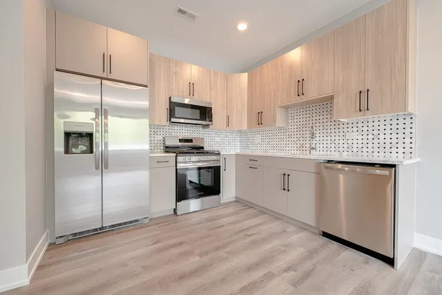 a kitchen with stainless steel appliances kitchen island granite countertop a sink a stove a refrigerator and cabinets