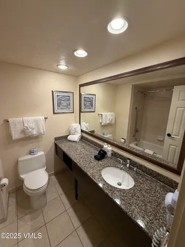 a bathroom with a granite countertop sink a mirror and a toilet