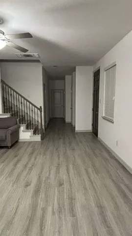 a view of an empty room with wooden floor and stairs