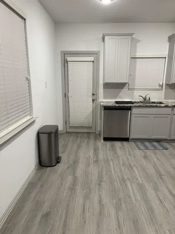 a kitchen with granite countertop a sink cabinets and wooden floor