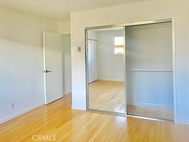 a view of an empty room with wooden floor and a bathroom