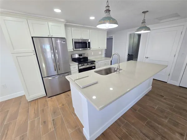 a kitchen with stainless steel appliances a refrigerator a sink a stove a microwave and island