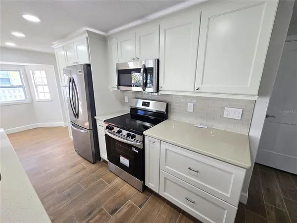a kitchen with white cabinets and stainless steel appliances