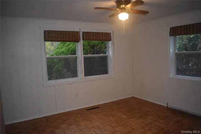 a view of empty room with wooden floor and fan