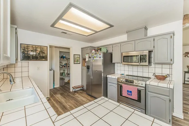 a open kitchen with stainless steel appliances granite countertop a refrigerator and a stove top oven
