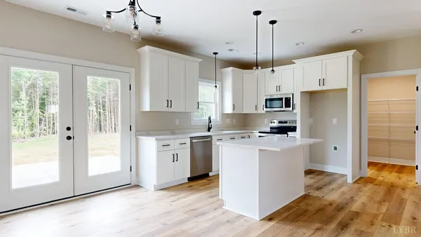 a kitchen with stainless steel appliances a stove top oven a sink a refrigerator white cabinets and wooden floor