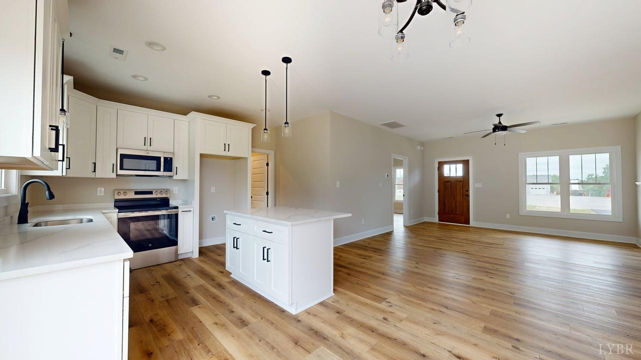 3729 Kentuck Road Ringgold, VA 24586 - Photo 9 of 42 a kitchen with granite countertop a stove a sink a refrigerator and white cabinets with wooden floor