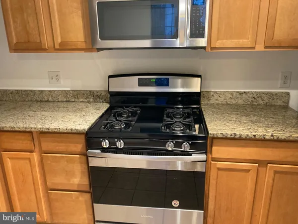 a kitchen with granite countertop cabinets stove top oven and microwave