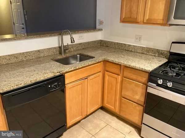 a kitchen with granite countertop a sink stove and cabinets