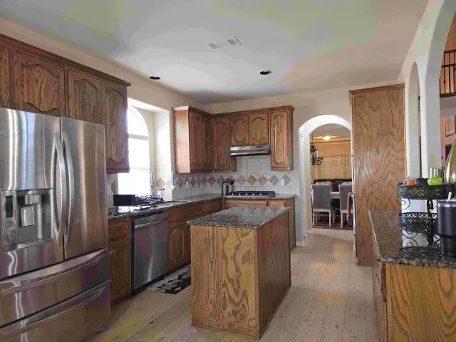 a kitchen with stainless steel appliances granite countertop a refrigerator a sink a stove and island