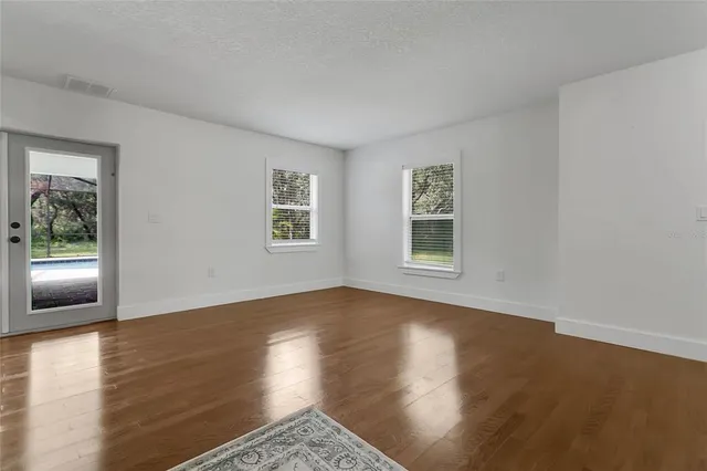 a view of an empty room with window and wooden floor