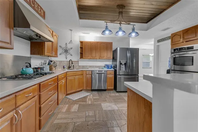 a kitchen with stainless steel appliances granite countertop a sink a stove a refrigerator cabinets and a dining table
