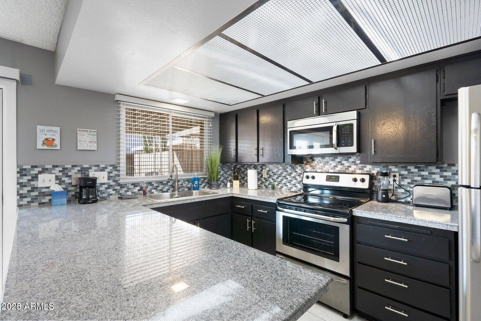 6921 East Osborn Road, Unit D Scottsdale, AZ 85251 - Photo 8 of 13 a kitchen with sink cabinets and stainless steel appliances