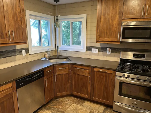 a kitchen with stainless steel appliances granite countertop a sink stove and microwave