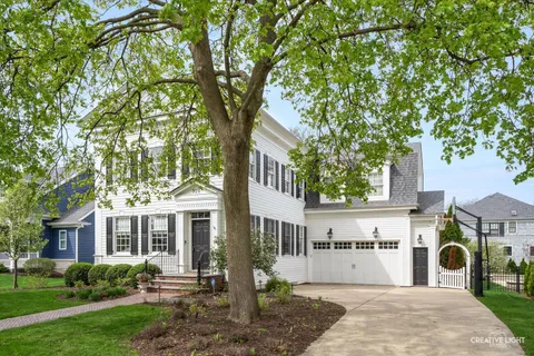a front view of a house with garden and trees