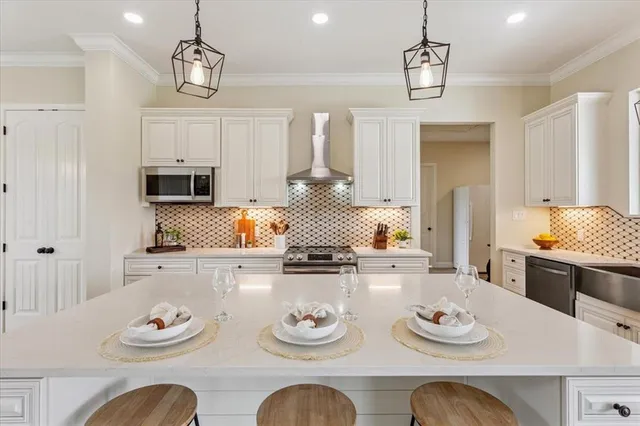 a kitchen with stainless steel appliances granite countertop a sink a stove a refrigerator and island with wooden floor