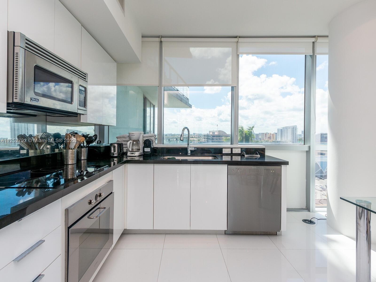92 Southwest 3rd Street, Unit 1510 Miami, FL 33130 - Photo 19 of 90 a kitchen with stainless steel appliances granite countertop a stove a sink and a granite counter tops with white cabinets next to a window