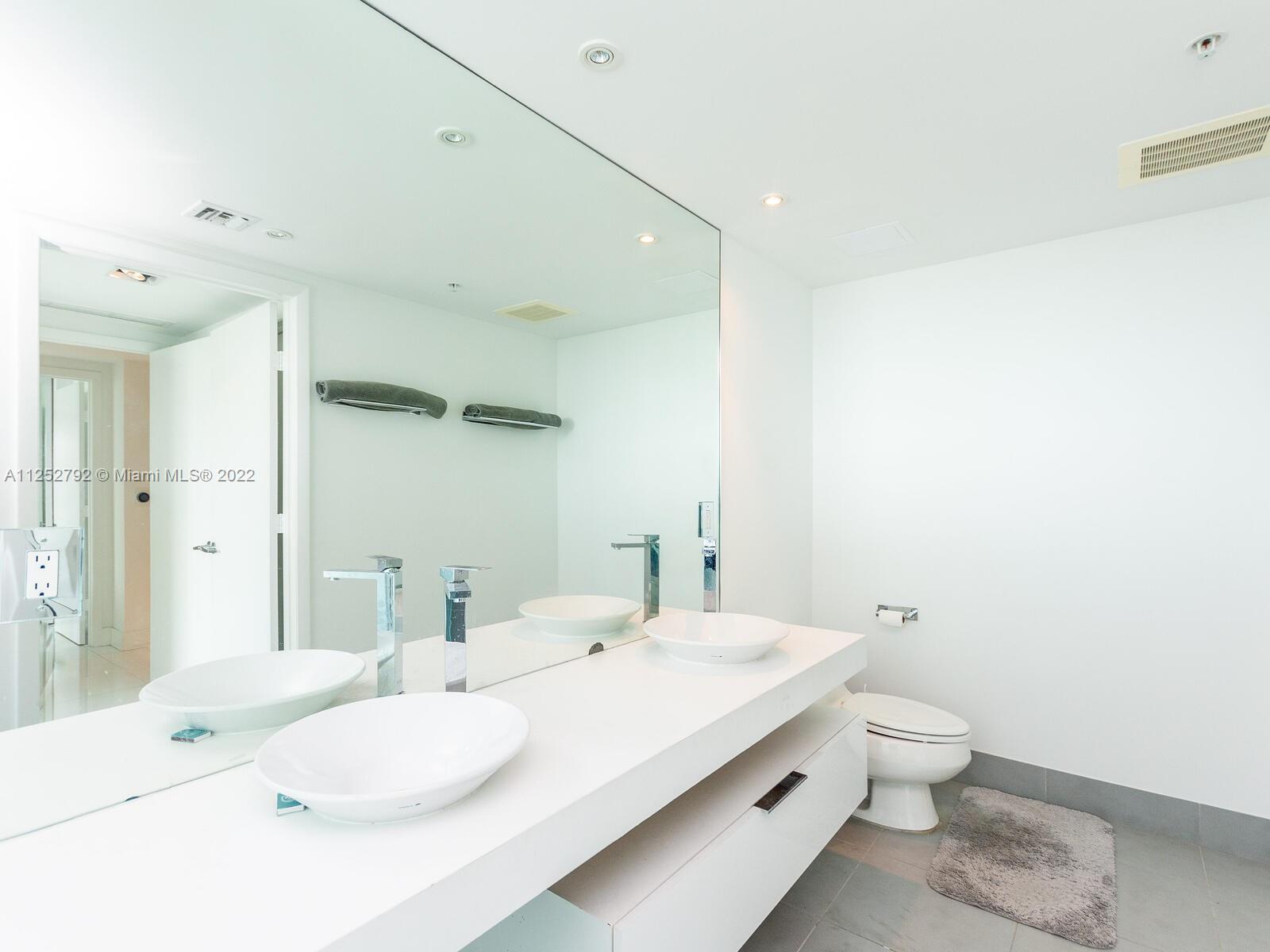 92 Southwest 3rd Street, Unit 1510 Miami, FL 33130 - Photo 30 of 90 a bathroom with a sink and mirror with toilet