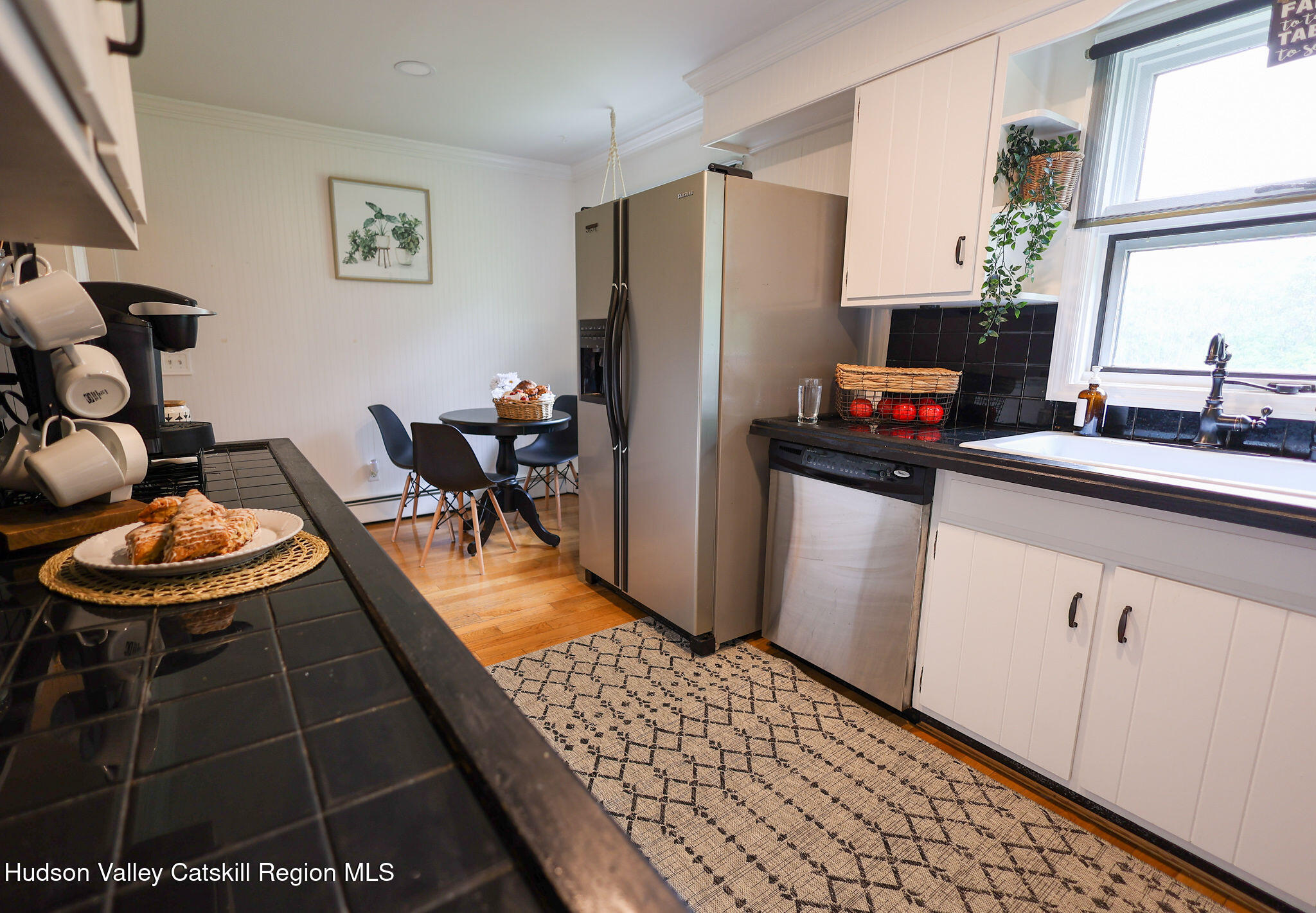 523 Mitchell Hollow Road Windham, NY 12496 - Photo 20 of 59 a kitchen with stainless steel appliances a sink a stove a refrigerator a dining table and chairs with wooden floor